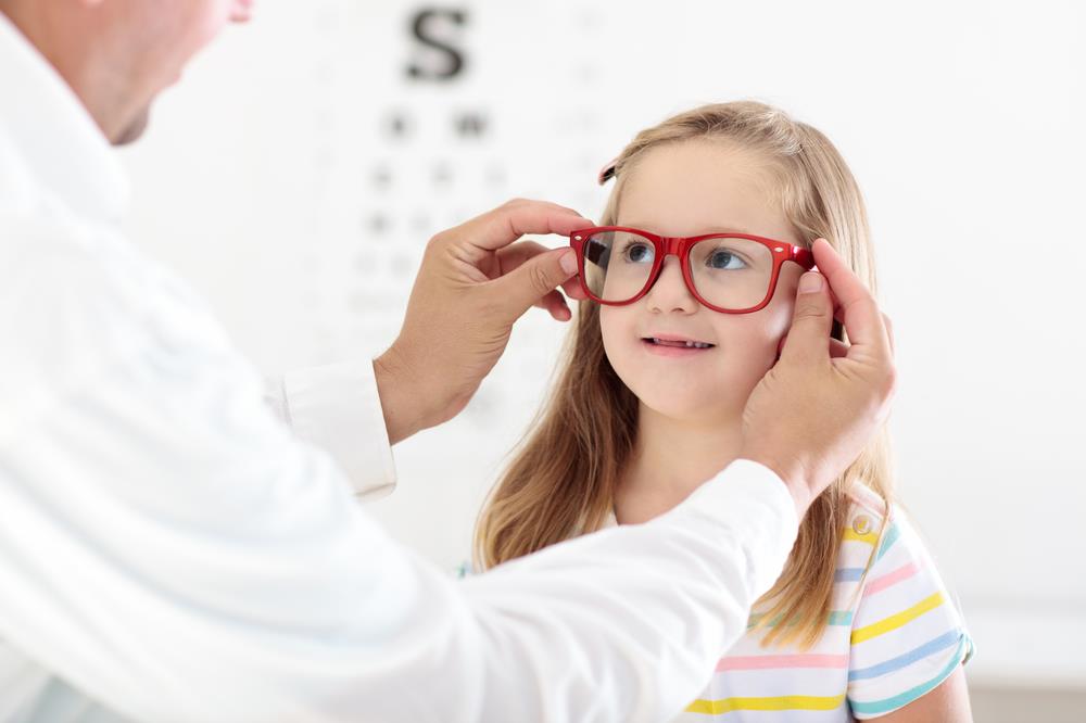optician fitting frames on a young girl