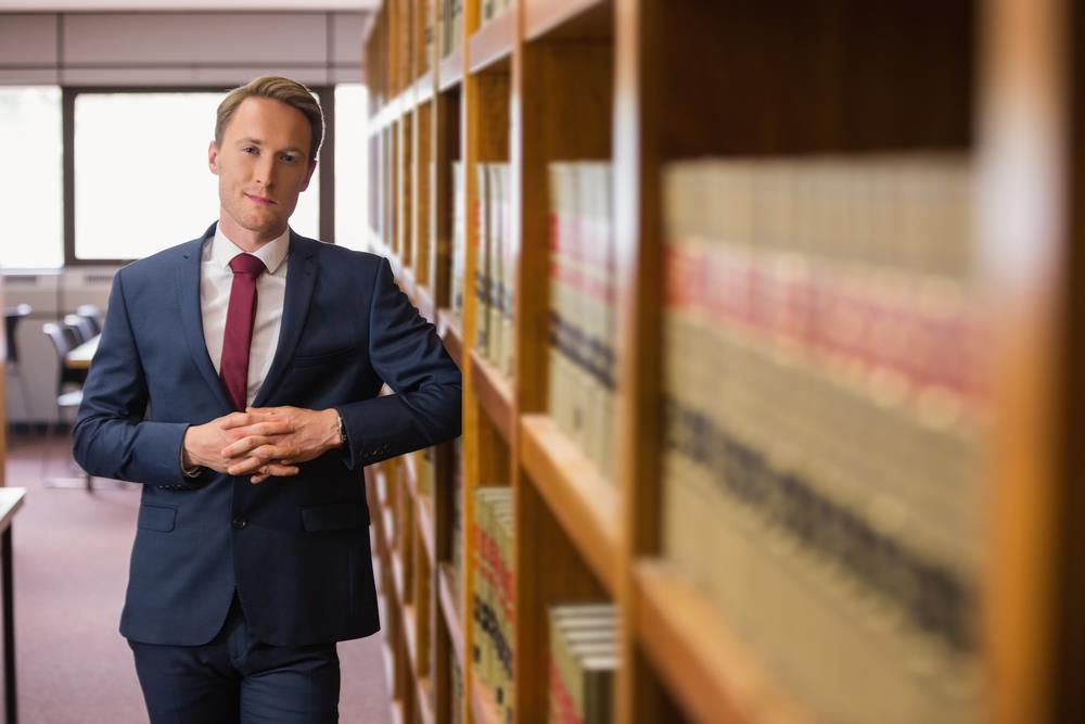legal assistant posing next two bookshelves full of law texts