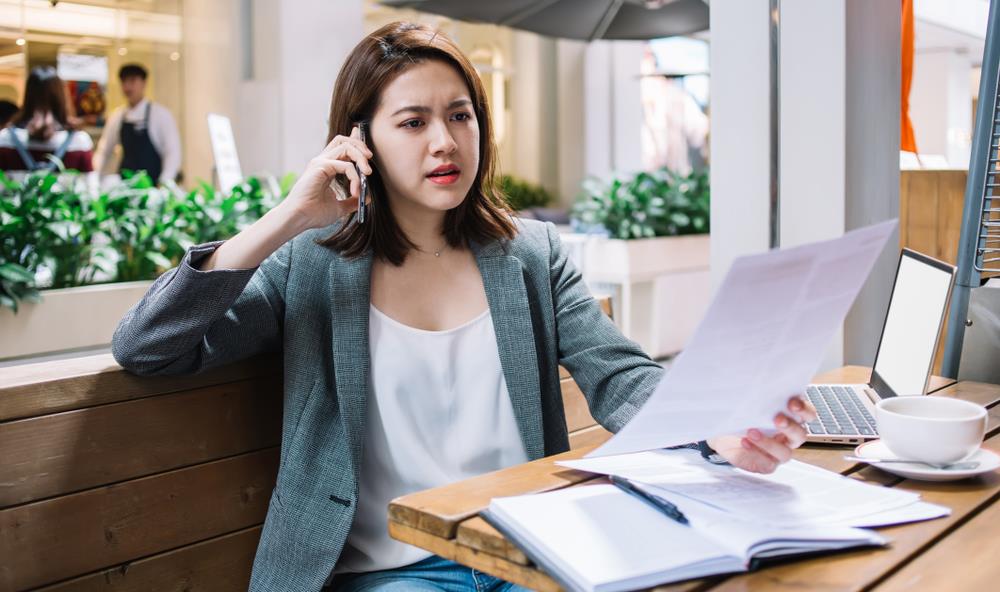 Upset business woman looking at a paper while on the phone