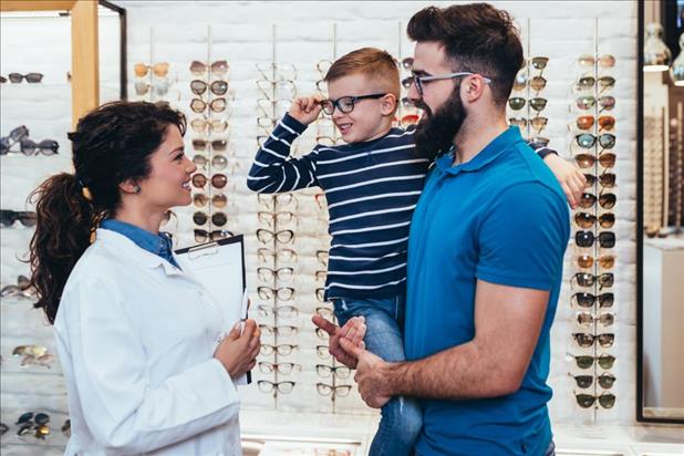 optometrist helping a father and son in her practice