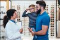 optometrist helping a father and son in her practice