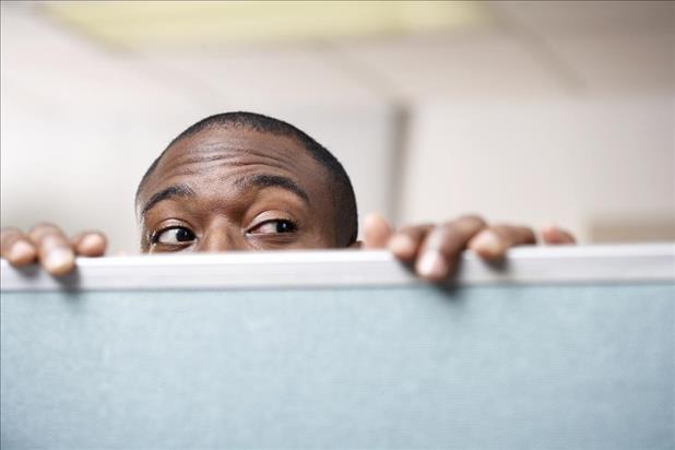 man peeking over a cubicle wall to learn about company culture