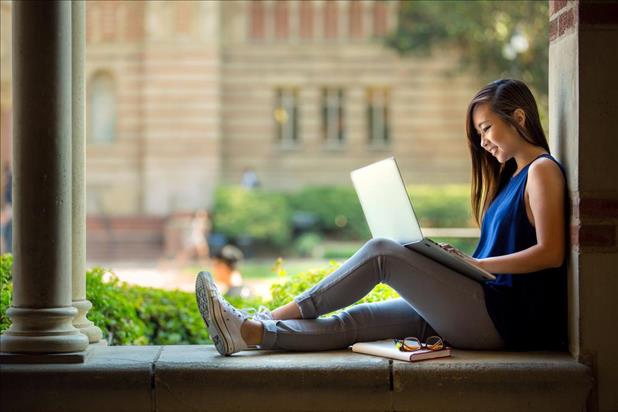 college freshman sitting outside on campus researching jobs online