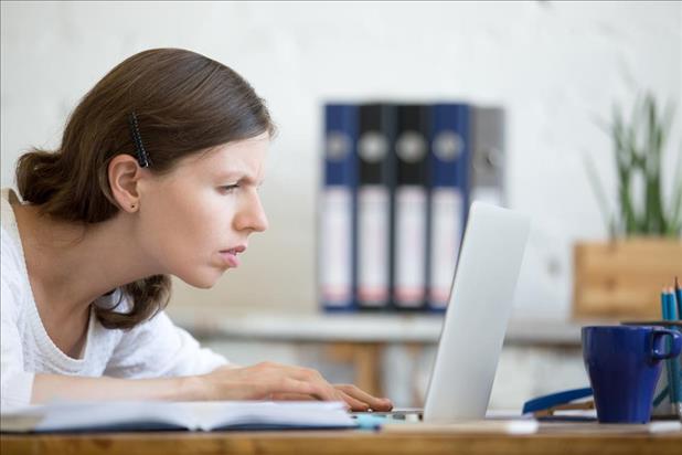 Woman squinting at resume on laptop