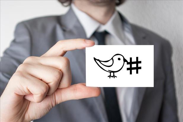 job seeker in a suit holding a business card with twitter bird and hashtag