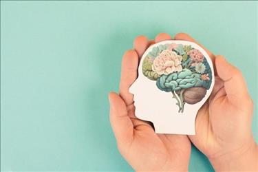hands holding an illustration of a brain with flowers in it