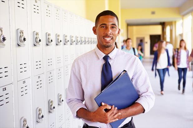Secondary teacher standing in front of row of lockers