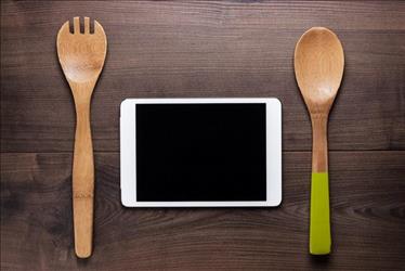 Two wooden cooking utensils on either side of a tablet