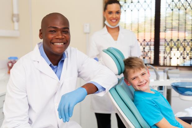 dentists with patient in chair smiling