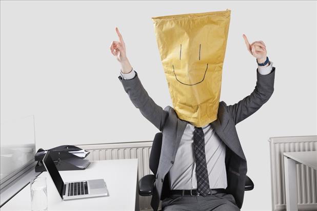 Businessman cheering with smile drawn on paper bag over face in office