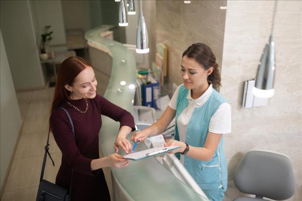 Dental office manager helping patient with paperwork