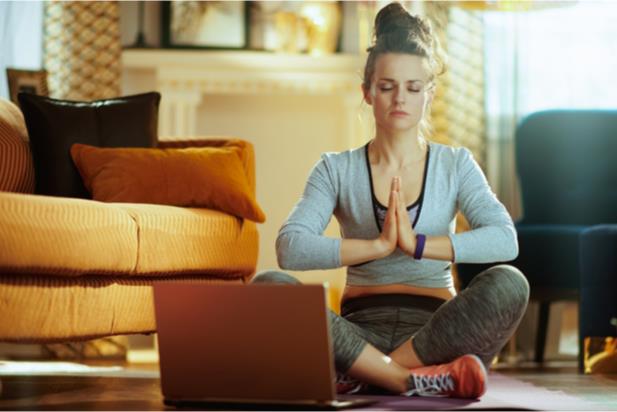 woman practicing yoga in front of laptop