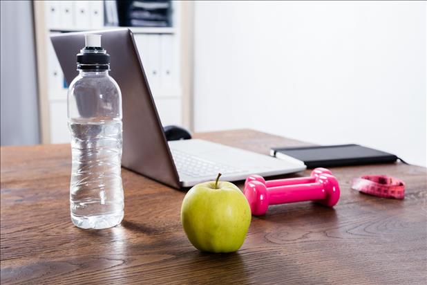 Desk with healthy food, weights, and laptop