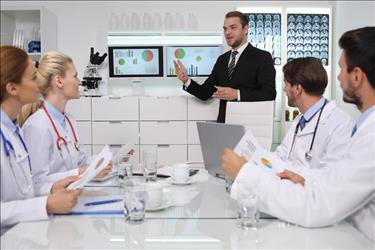 healthcare administrator giving a presentation to a team of doctors