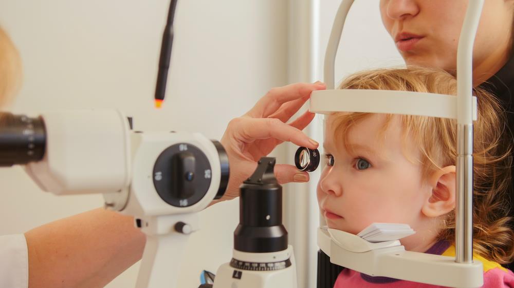 child sitting in her parent's lap getting her eyes tested
