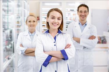 happy pharmacy manager standing in front of her two happy pharmacy employees