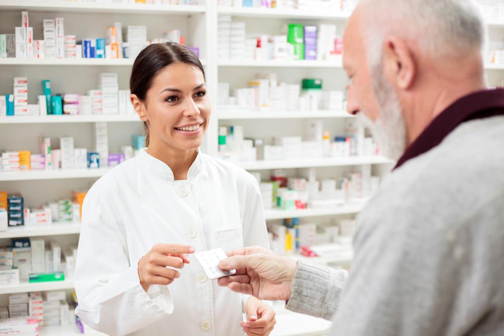 pharmacist taking a customer's insurance card to process an order