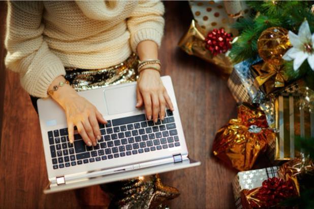 person typing on laptop near christmas tree