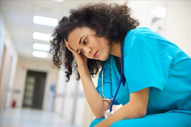discouraged nurse at work with her head in her hand