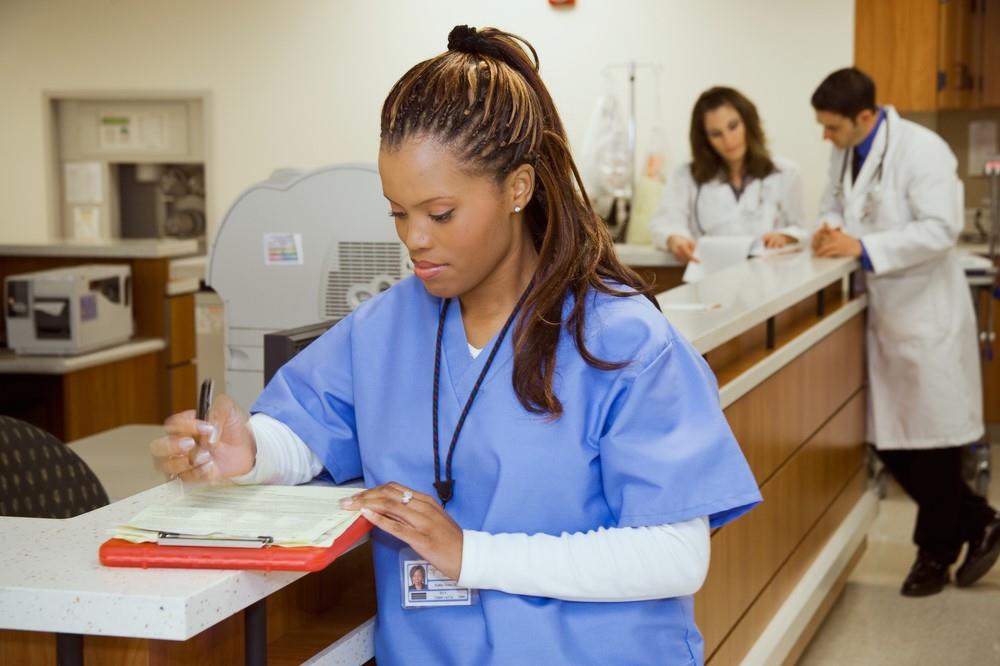 nurse updating a patient's chart at the reception desk