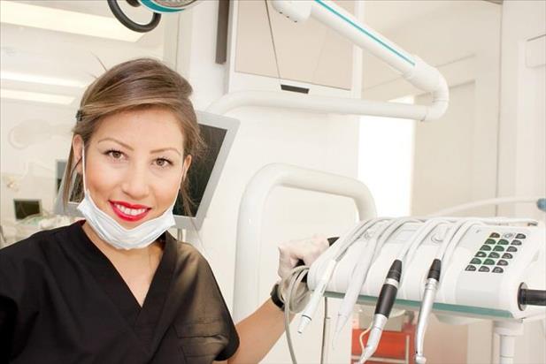 Dentist posing in front of machinery in examination room