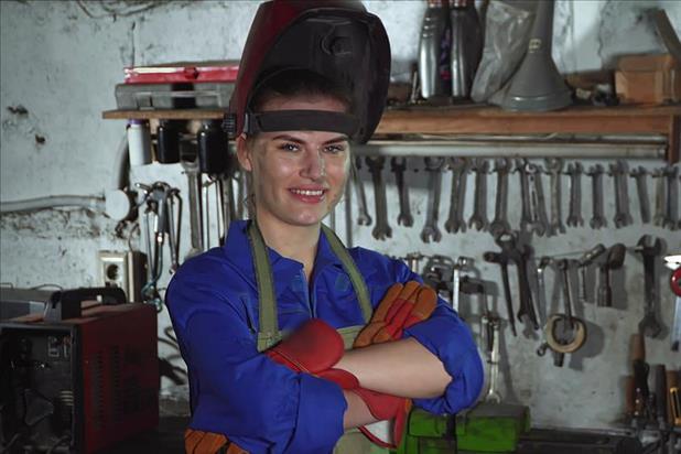 a welder in the workshop smiling with her arms crossed