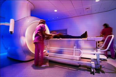 patient receiving an mri with help from two radiologic technoloigsts