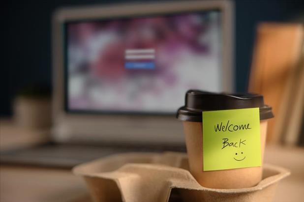 coffee cup on desk with note welcoming employee back to the office