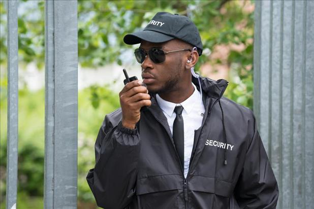 security guard patrolling outside with a two-way radio