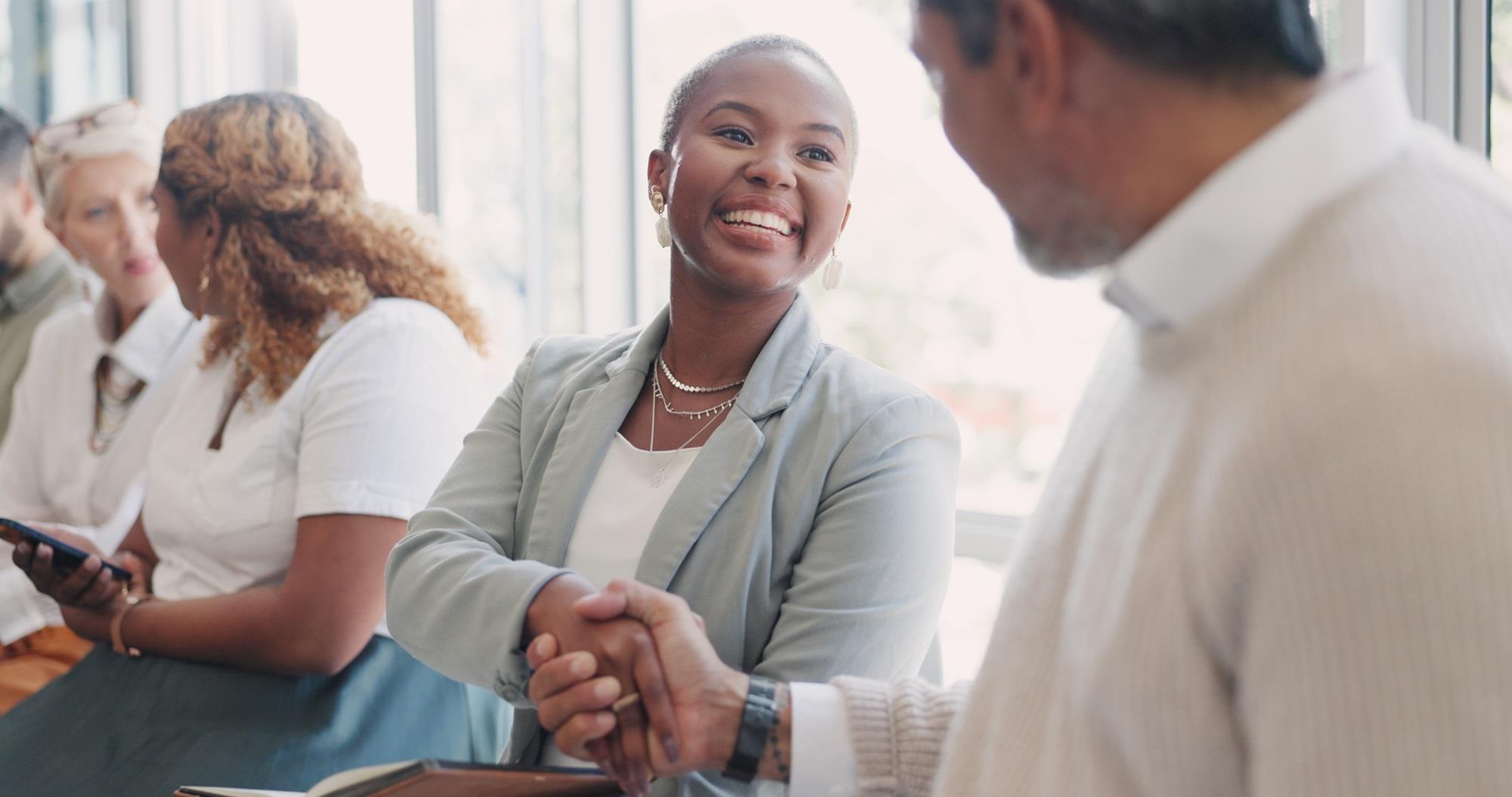 smiling woman shaking hands with a man seated next to her