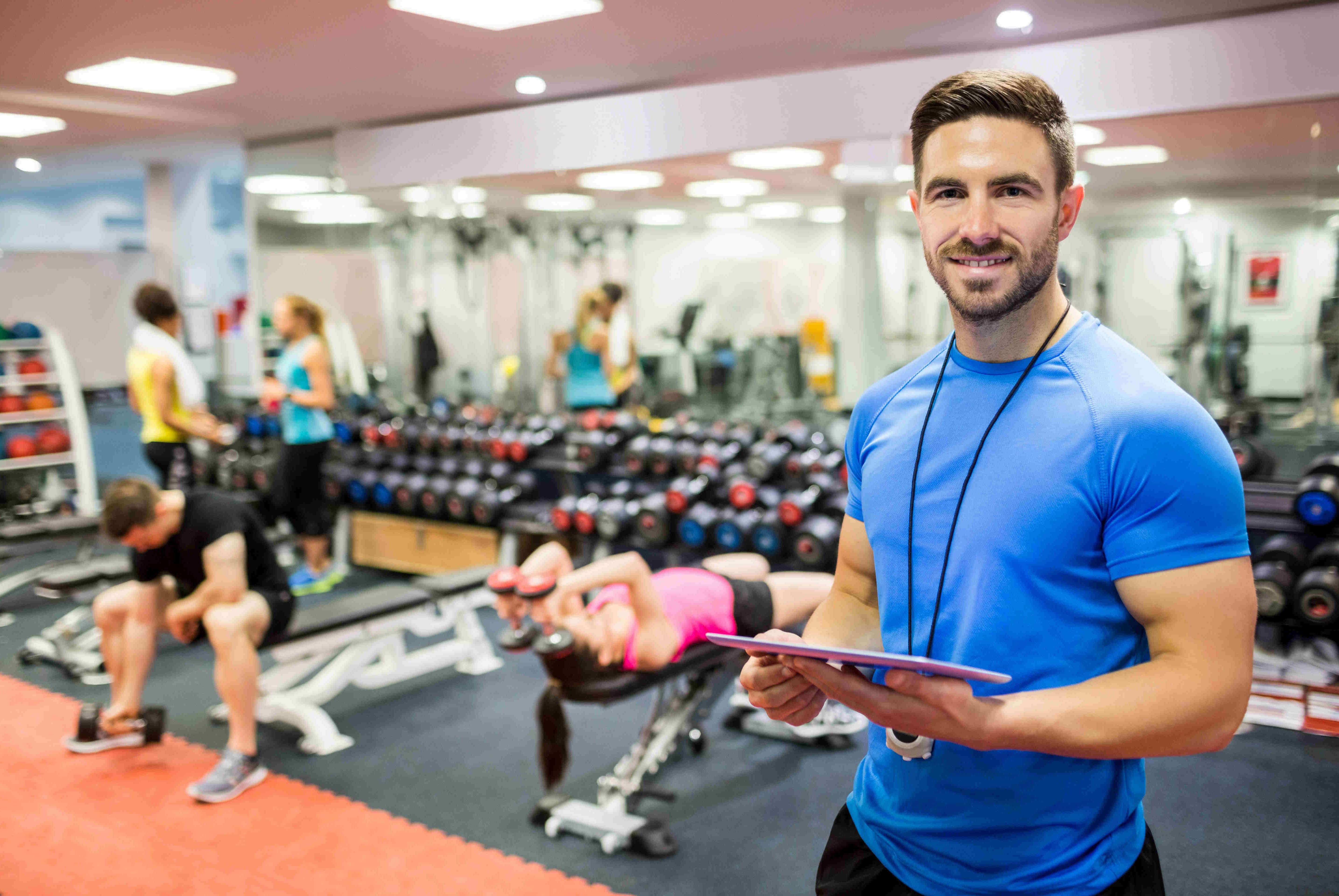 Personal trainer smiling with people exercising in the background