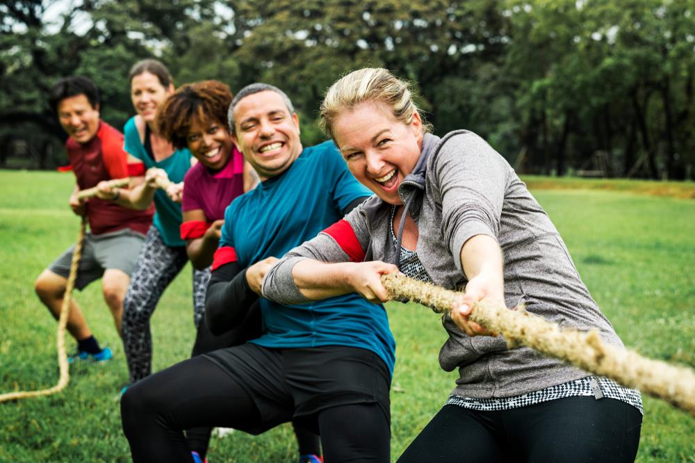 diverse team playing tug of war during a team building event