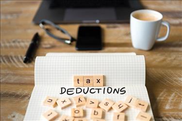 paper on a desk with tax deductions spelled out in ink and tiles